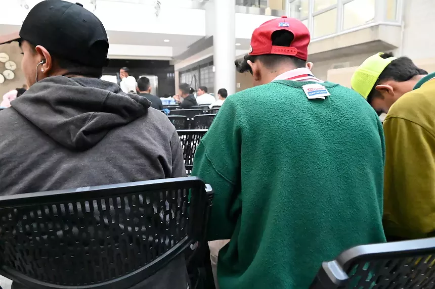 Miguel Alvares and two friends sitting in the new migrant intake center in Denver, Colorado.