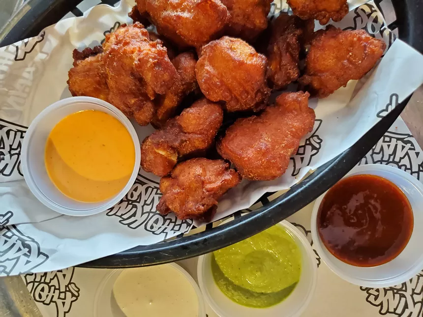 a basket of fried chicken nuggets with dipping sauces