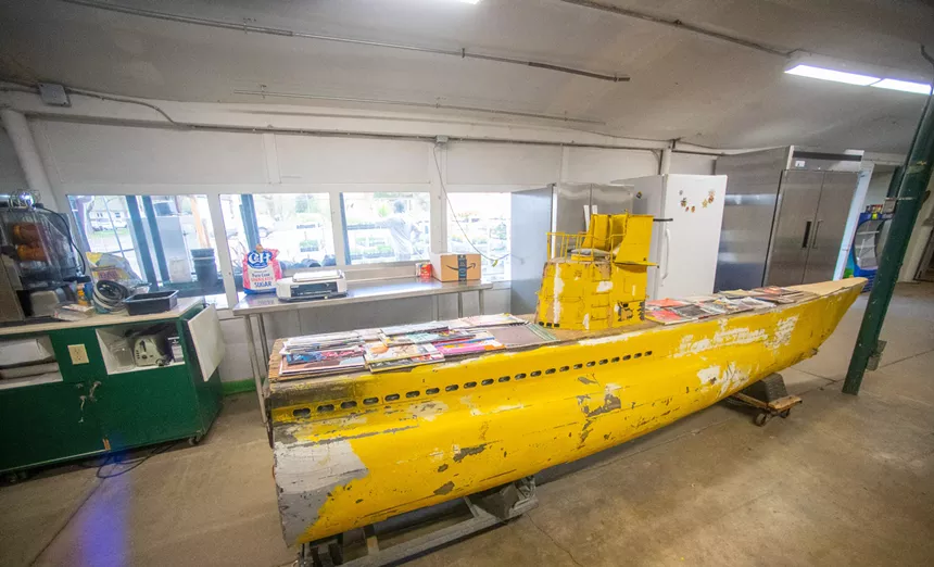 an old, small yellow submarine inside a store with magazines on top
