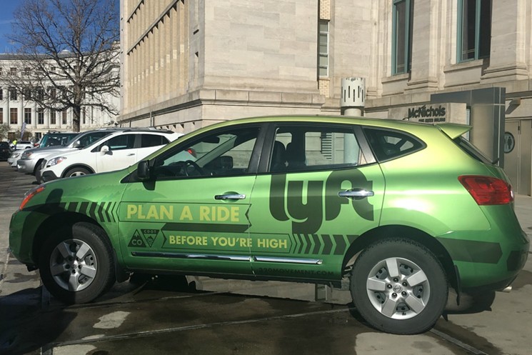 A green sedan emblazoned with Lyft on the side sits outside the Colorado state capitol.