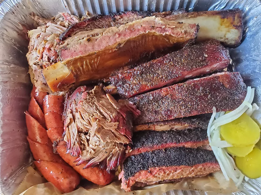 a tray of barbecue including ribs,  sausage and pilled pork