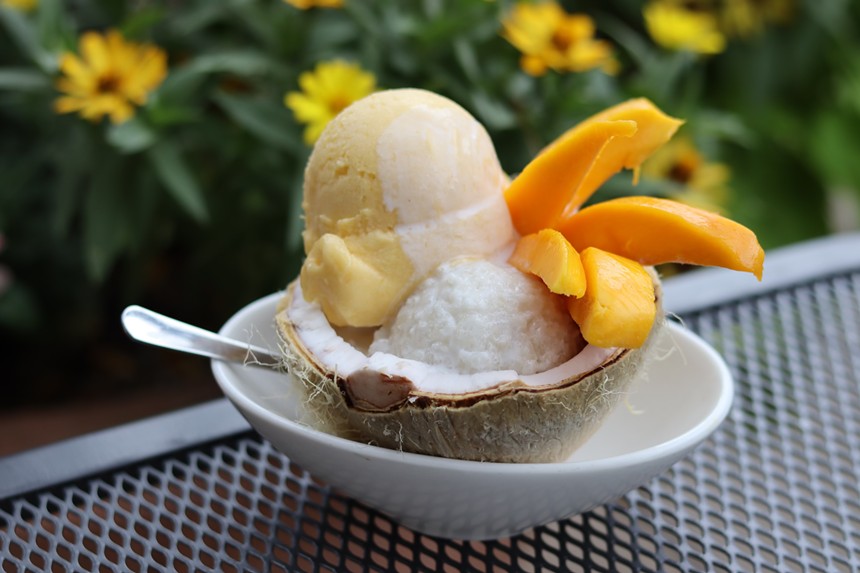 A halved coconut filled with sorbet, mango slices and cream