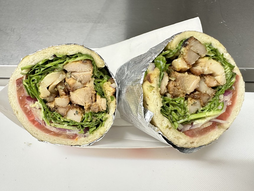 a chicken gyro wrapped in a pita with tomatoes and arugula