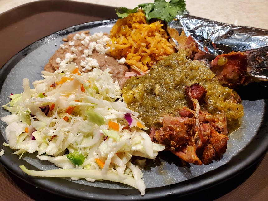 a plate of carnitas with green sauce on top