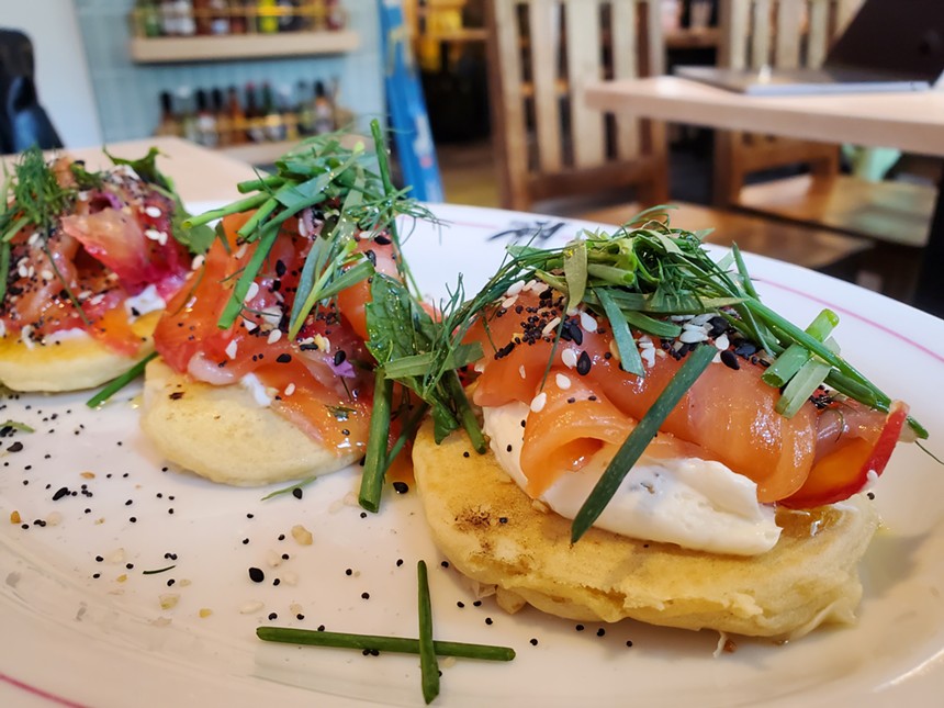small pancakes topped with lox, cream cheese and herbs