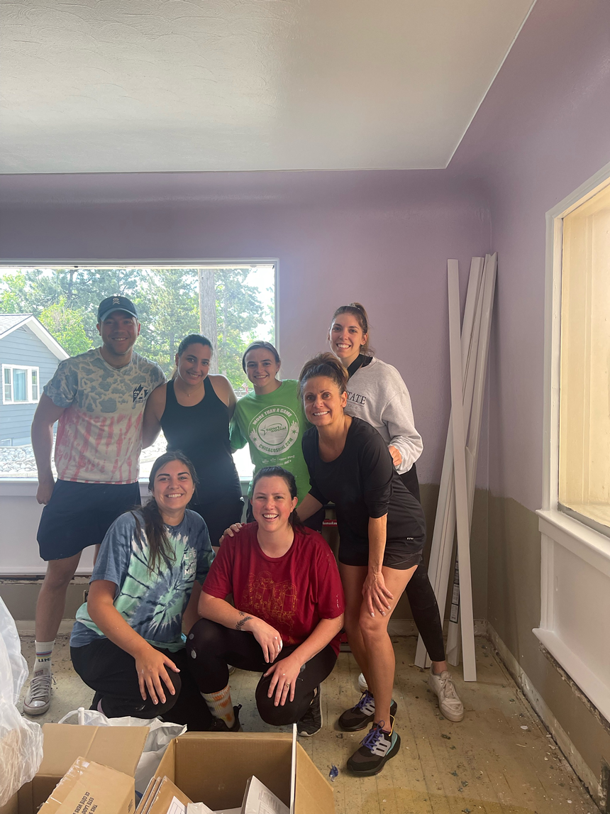 Seven people stand in a lavender room