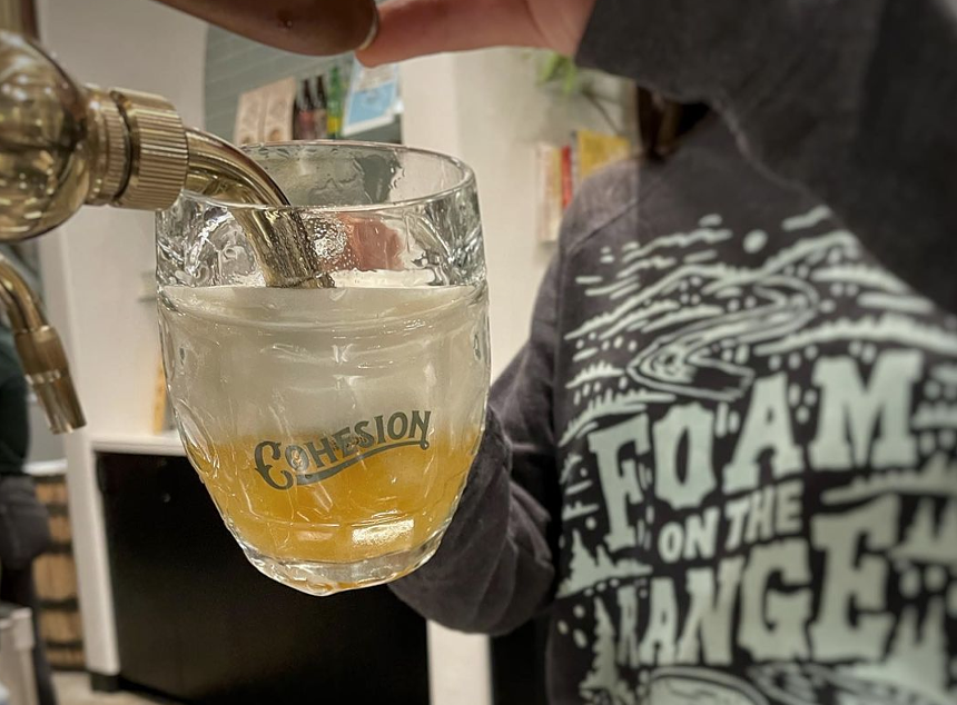 a person pouring beer into a mug from a tap