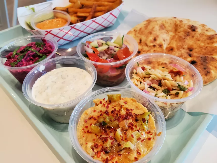 small plastic cups filled withv a variety of dishes on a tray with a pita