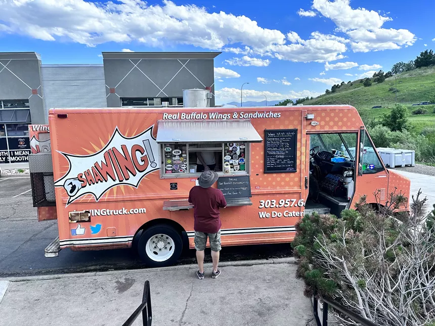 a man standing in front of an orange food truck