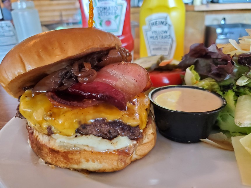 a bacon cheeseburger in front of bottles of ketchup and mustard