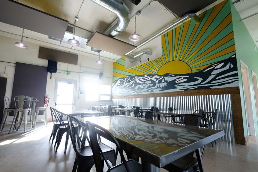 a large table with chairs in a room with a mural depicting the sun over mountains