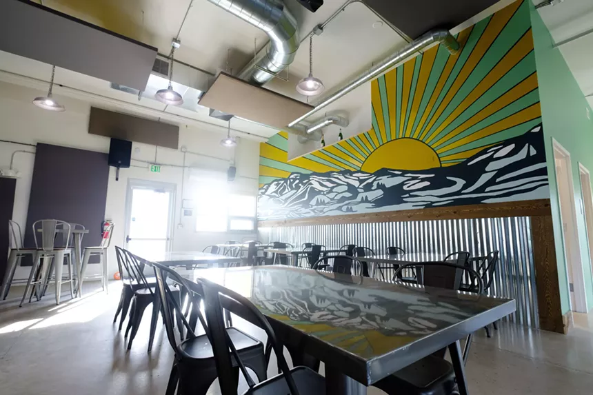 a large table with chairs in a room with a mural depicting the sun over mountains