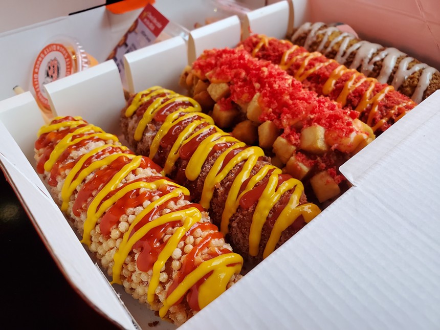 a box filled with corn dogs with different toppings