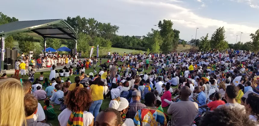 a crowd of people on a hill looking at an outdoor stage