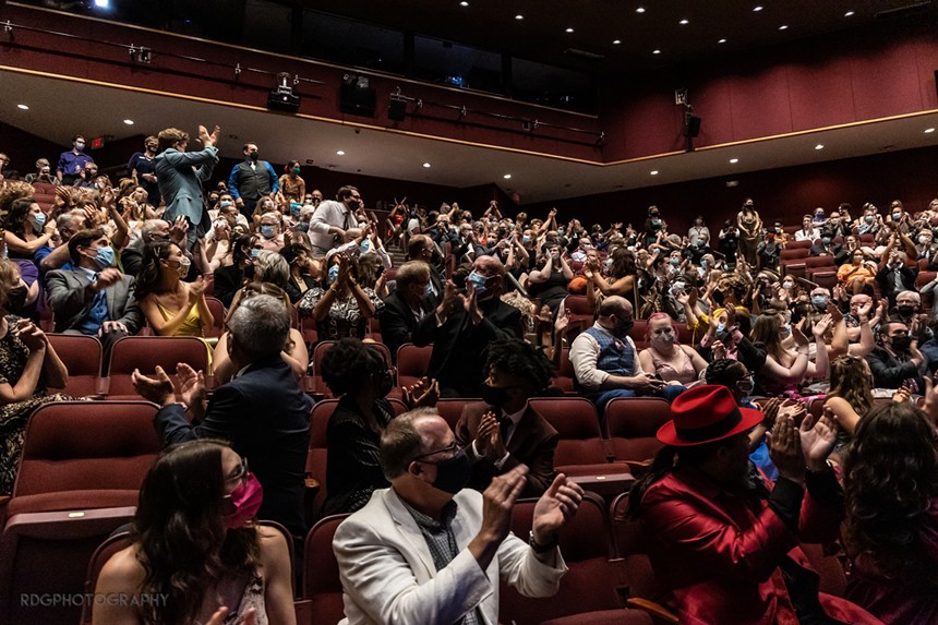a crowd clapping in an auditorium