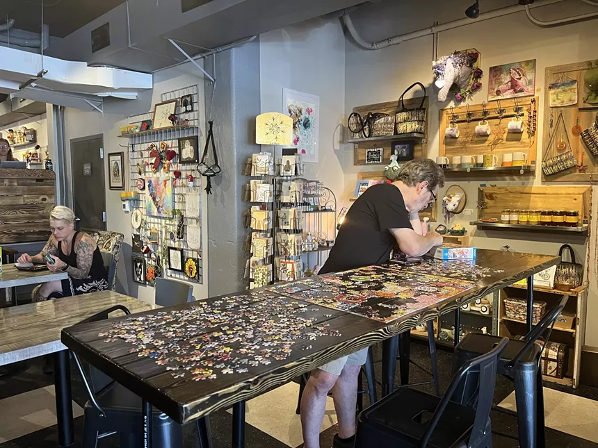 a person standing behind a table covered in puzzle pieces