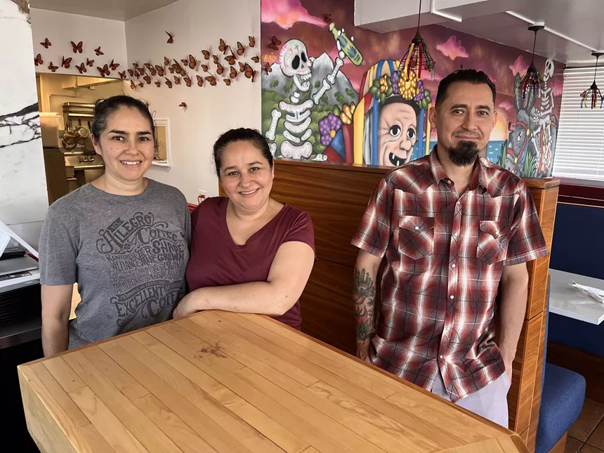 two woman stand behind a table next to a man in a plaid shirt