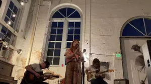 woman musician at mike in old industrial building.