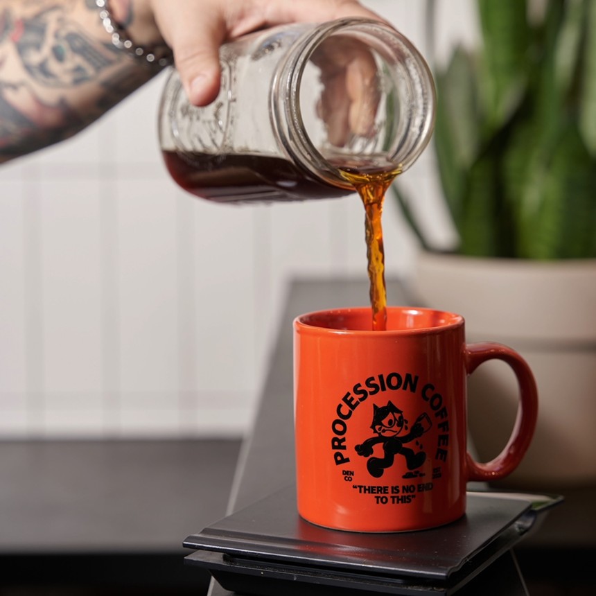 hand pouring coffee from a mason jar into an orange mug