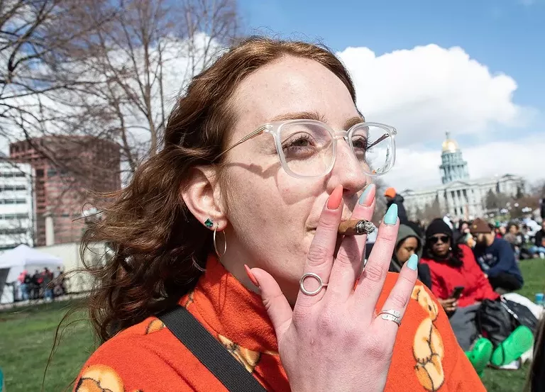 A woman smokes a blunt at Civic Center Park in Denver