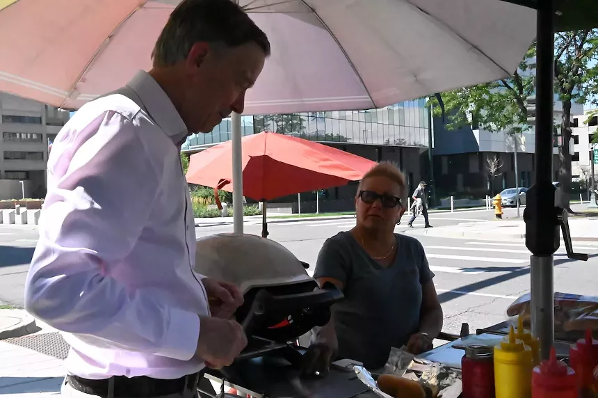 John Hickenlooper tops his bratwurst in front of Marcella Armas at her hot dog cart on 14th Avenue and Cherokee Street.