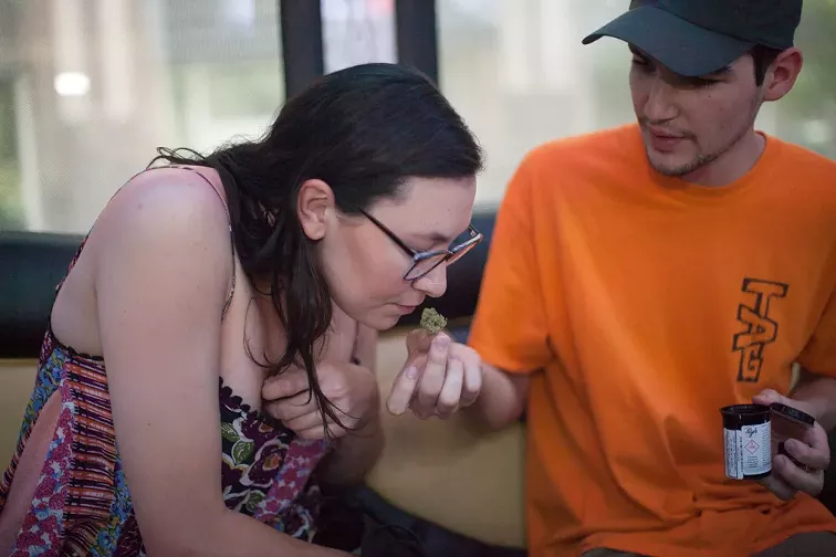 A woman smells a marijuana bud aboard a tour bus