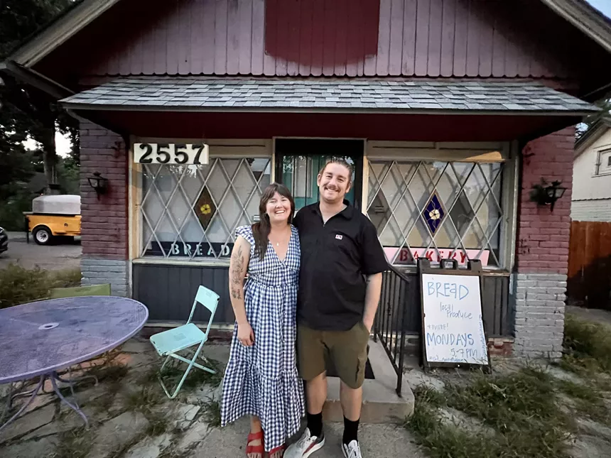 a woman and a man in front of a pink building