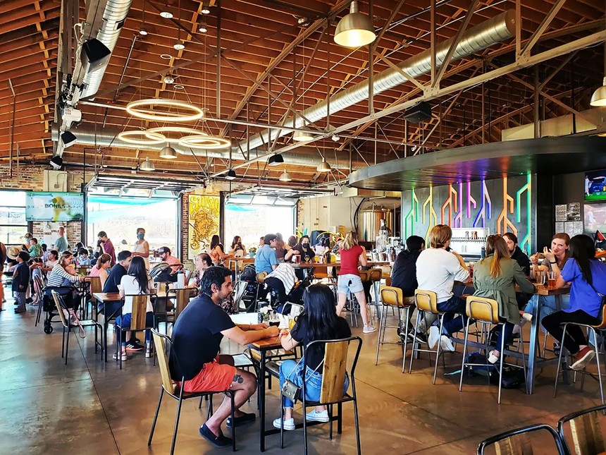 people sitting at tables inside a brewery taproom