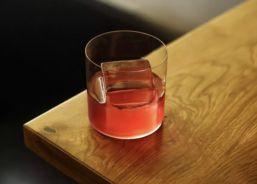 red drink in clear glass sits on wooden table