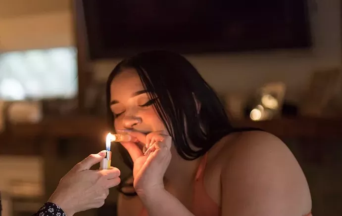 A woman smokes weed from a chillum