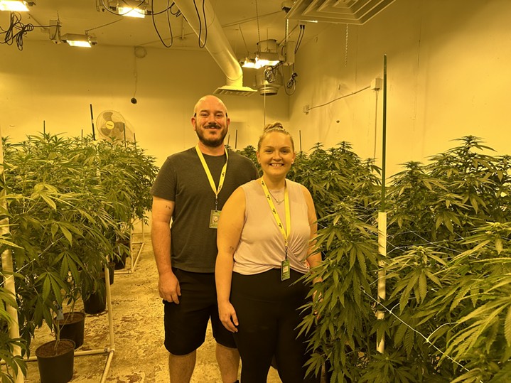 A couple stands in front of their legal cannabis cultivation