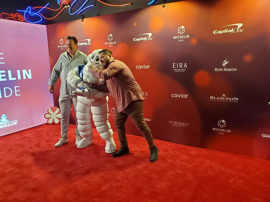 two men posing with the Michelin tire mascot