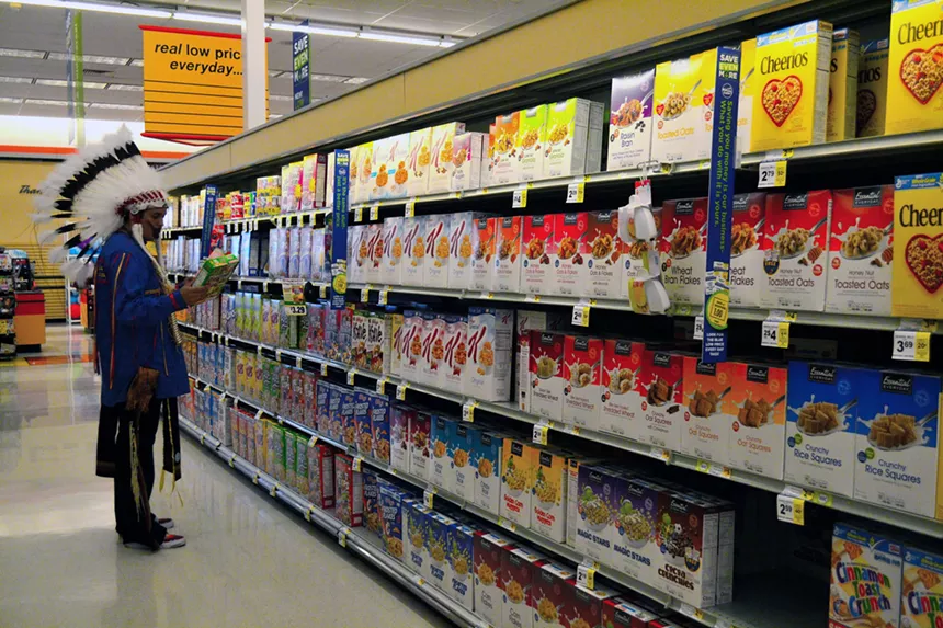 man wearing feather headdress looking at cereal