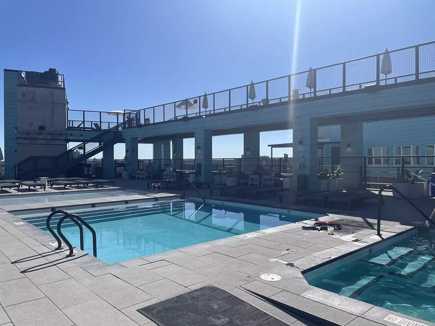 A concrete-lined pool with a balcony and chairs.