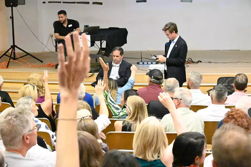 People raise their hands during a town hall with Mayor Mike Johnston.