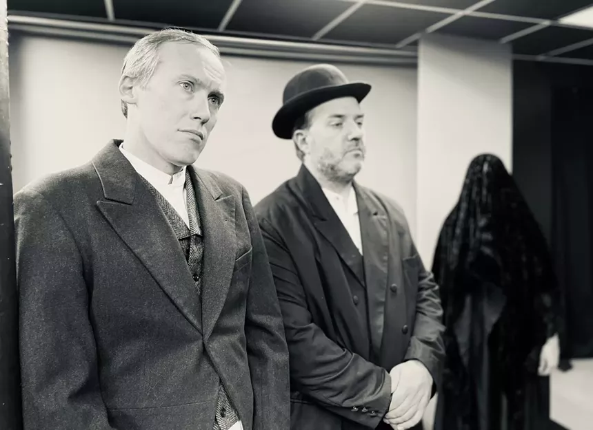 two men in suits with a ghostly black figure behind them