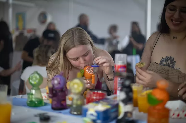 A woman takes a dab of hash at a cannabis event.