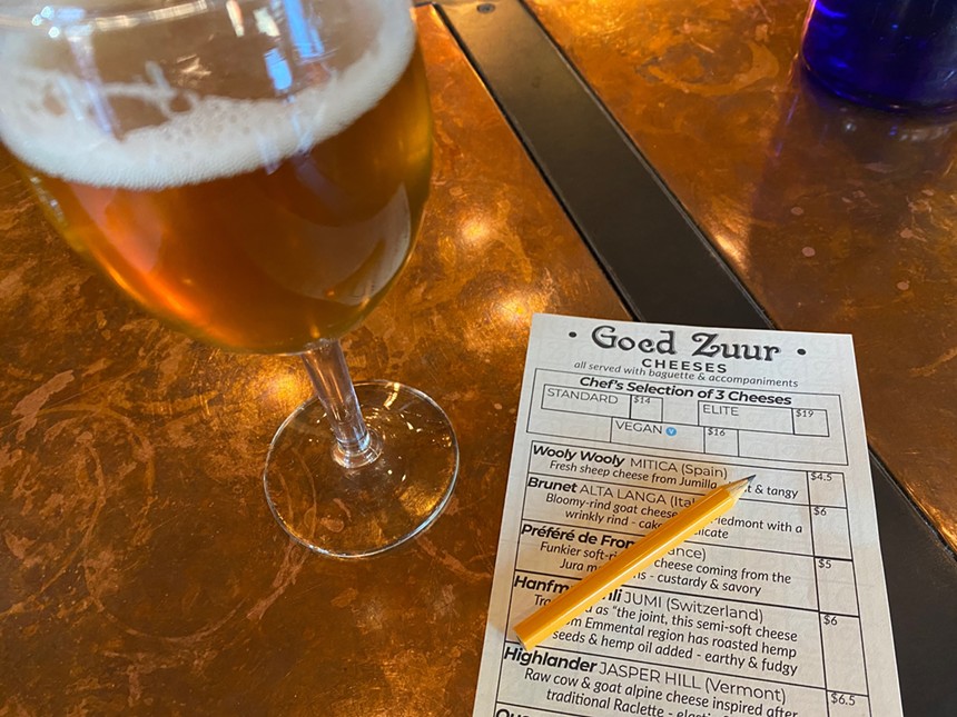 a glass of beer next to a piece of paper and a small pencil