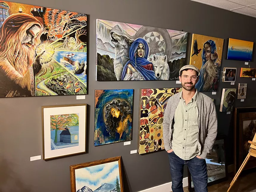 a man standing in front of a wall with framed paintings