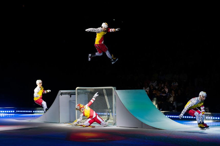 men on ice skates and in hockey outfits skating over a ramp