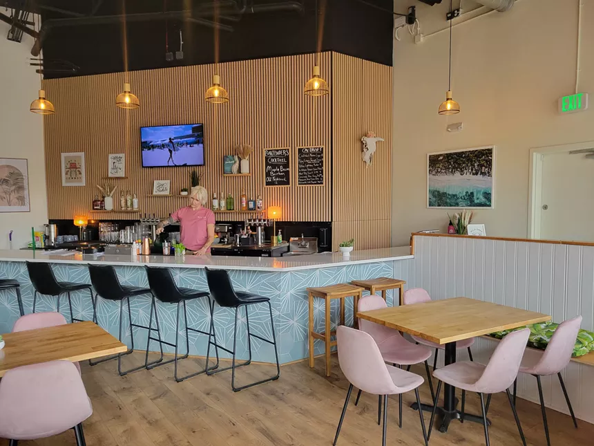 blue bar with worker and pink chairs at tables