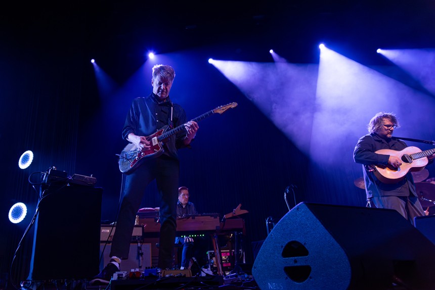 two men playing guitar on stage in blue lighting