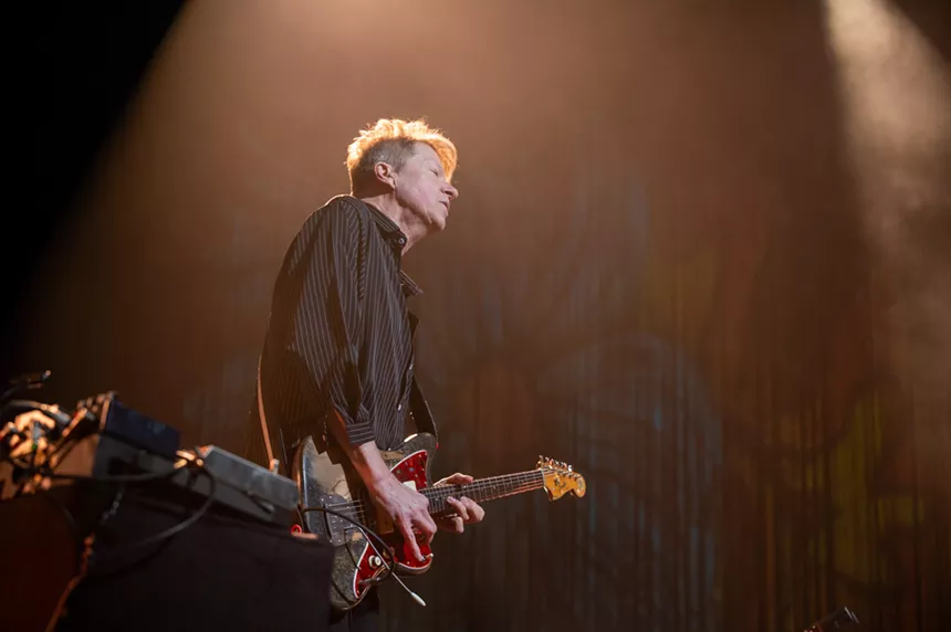 man playing guitar on stage in button up shirt