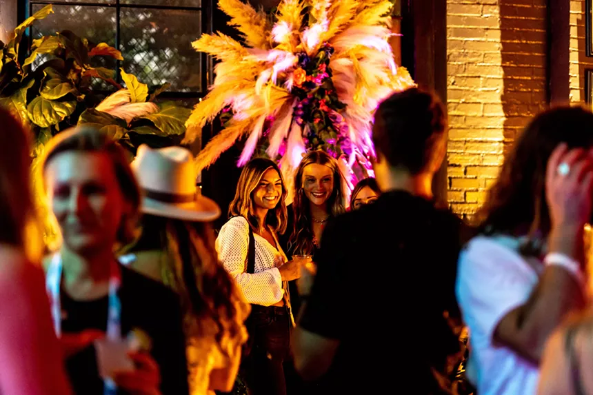 women in a bar with plants and pink and yellow lighting