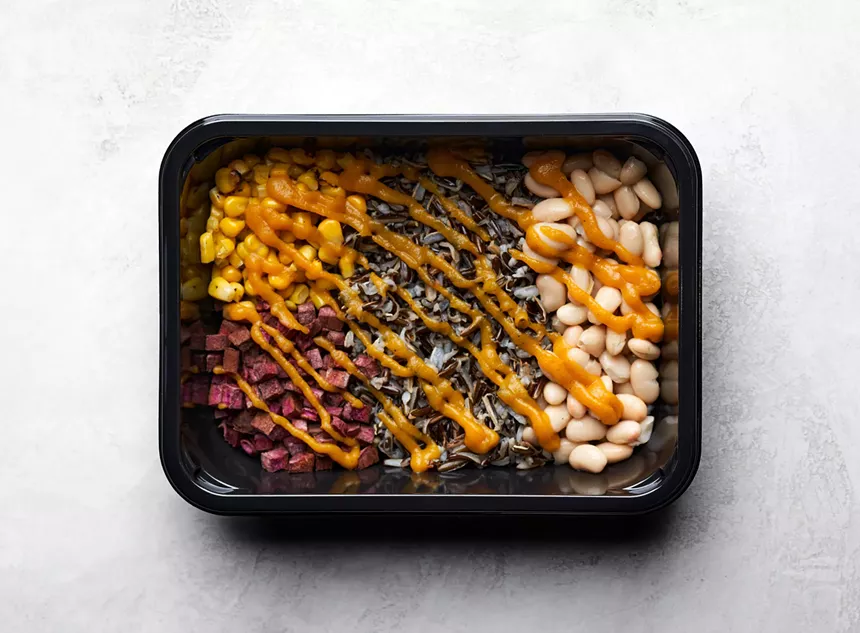 black container with food in it on white table