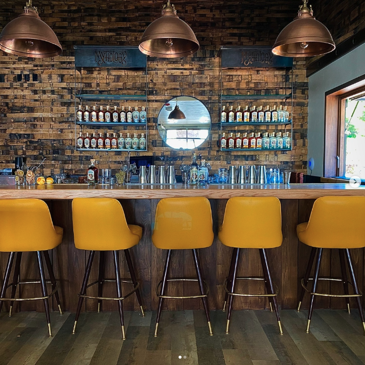 yellow stools lined up in front of a wooden bar