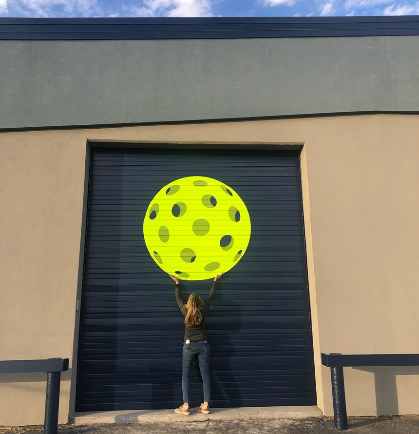 woman standing in front of a pickleball mural