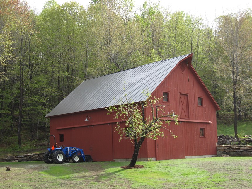 Large red barn with trees in background.
