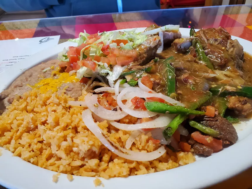 a plate of rice, beans and pork with chiles