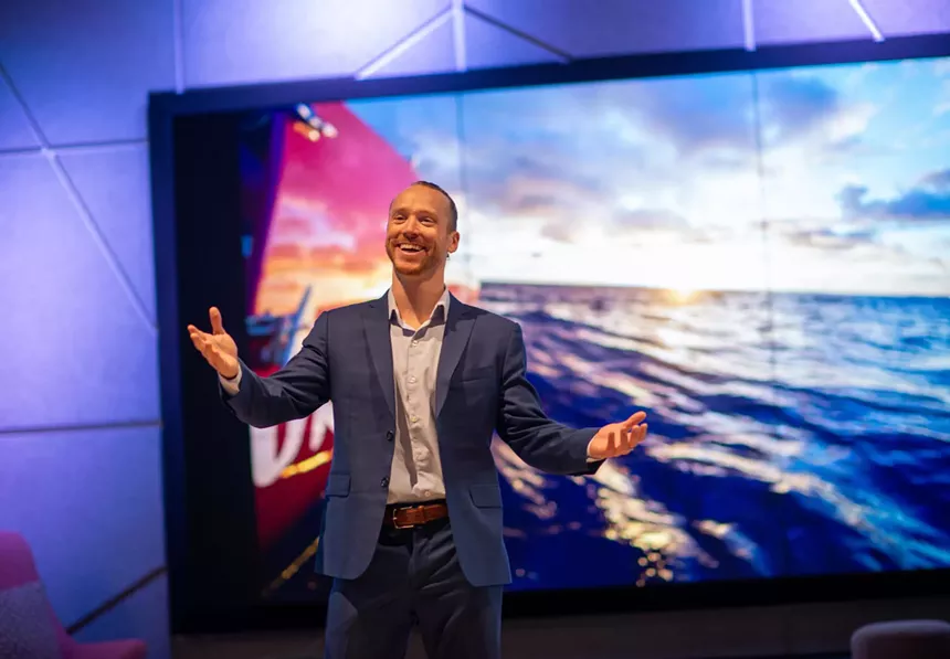 man in suit talking in front of screen